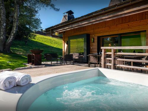 a hot tub on a deck next to a house at Chalet RevAlp - OVO Network in Combloux