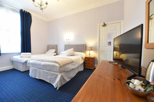 a bedroom with two beds and a flat screen tv at Ashwood Hotel in Preston