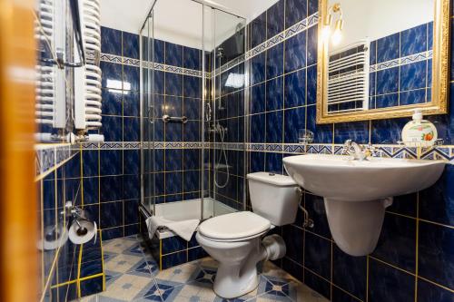a blue tiled bathroom with a toilet and a sink at Hotel Europa in Polanica-Zdrój