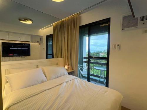 a bedroom with a white bed and a balcony at Belle Maison in Pine Suites Tagaytay in Tagaytay