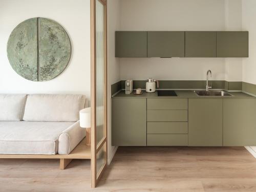 Kaoma Comfort Suites في تريكالا: مطبخ مع خزائن خضراء وأريكة