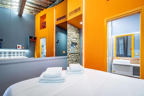a bathroom with orange walls and a bed with towels at Pop Tower Florence in Florence