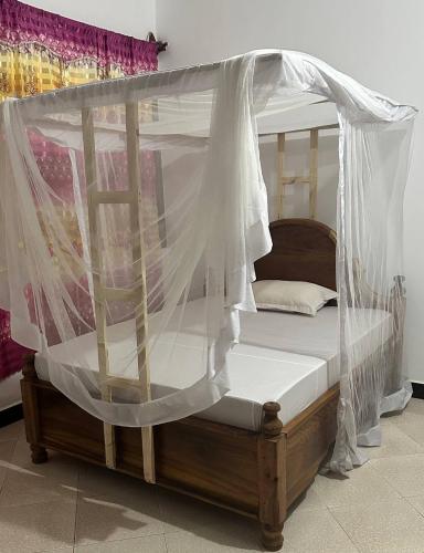 een hemelbed met witte klamboes erop bij Кокосовый домик in Nungwi