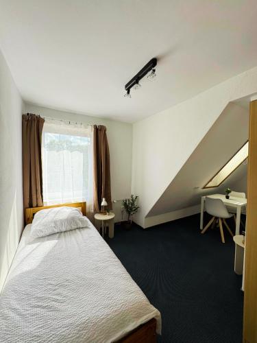 a bedroom with a bed and a window and a desk at die GastHütte in Eisenhüttenstadt