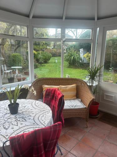 a conservatory with a table and a wicker couch and a table and window at Spacious Holiday Home! in London