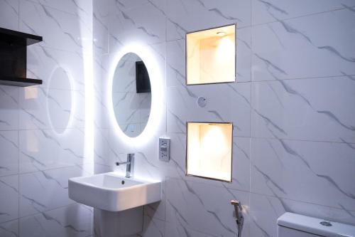 a bathroom with a sink and two mirrors at Main Avenue Residence Lagos in Lagos