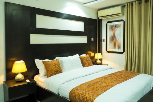 a bedroom with a large bed and two lamps at Main Avenue Residence Lagos in Lagos