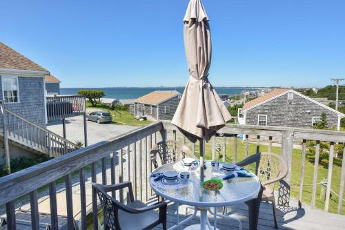 a table with an umbrella and chairs on a balcony at 12217 - Beautiful Views of Cape Cod Bay Access to Private Beach Easy Access to P-Town in Truro