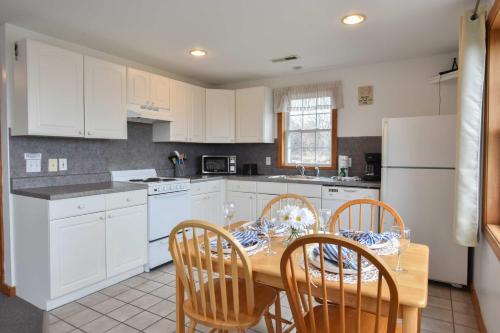 a kitchen with a table and chairs and white cabinets at 12217 - Beautiful Views of Cape Cod Bay Access to Private Beach Easy Access to P-Town in Truro