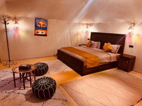 Un dormitorio con una cama tamaño king y una mesa. en Dream Luxury Majestic Camp, en Merzouga