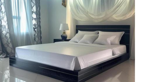 a bedroom with a large white bed with a black headboard at Villa Maurice in Mbour