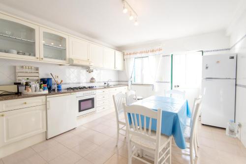a kitchen with white cabinets and a table and chairs at Vila Apartment - Duna Parque Group in Vila Nova de Milfontes