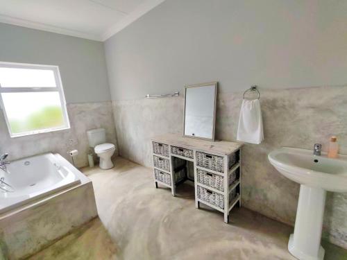 The Fifth Tee Villa في Stompneusbaai: حمام مع حوض وحوض استحمام ومرآة