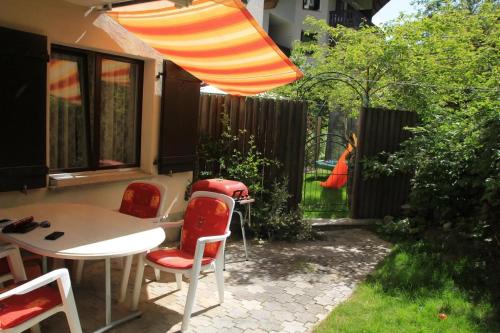 eine Terrasse mit Tisch und Stühlen und einem Sonnenschirm in der Unterkunft 1 12 Zi Wohnung mit persönlichem Charme - b48574 in Vulpera
