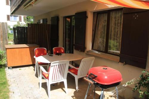 eine Terrasse mit einem Tisch, Stühlen und einem Grill in der Unterkunft 1 12 Zi Wohnung mit persönlichem Charme - b48574 in Vulpera