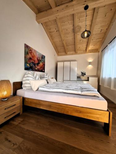 Cute House with terrace and garden في إنسبروك: غرفة نوم بسرير كبير في غرفة ذات أسقف خشبية
