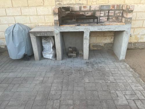 a stone table with a bench next to a brick wall at Seafront house in Swakopmund