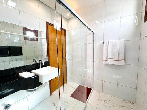 a bathroom with a sink and a glass shower at Eficiência - Casa Recanto dos Ventos in Camocim