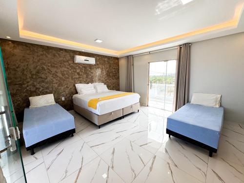 a hotel room with two beds and a window at Eficiência - Casa Recanto dos Ventos in Camocim