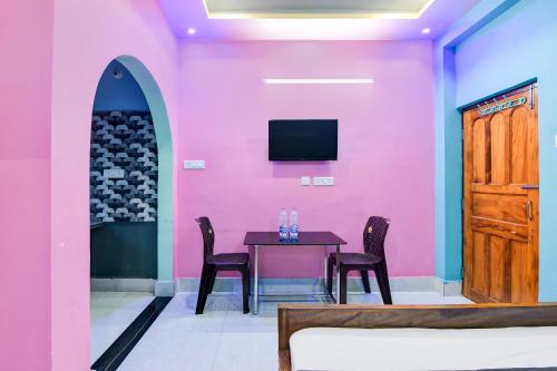Hotel O Subharaj palace 2 في كولْكاتا: غرفة طعام بجدران وردية وطاولة وكراسي
