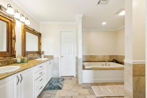 ein weißes Badezimmer mit zwei Waschbecken und einer Badewanne in der Unterkunft Waterfront Getaway • Balcony + Bayou Views in Lafitte