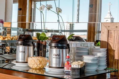 a counter with two coffee machines on a table with dishes at Hotel Santa Maria in Campo Mourão