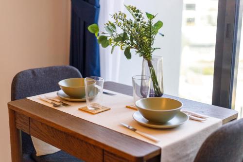 a wooden table with two bowls and a vase with flowers at Roomook Apartments in Dubai