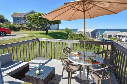 a table and chairs with an umbrella on a balcony at Beautiful Views of Cape Cod Bay in Truro