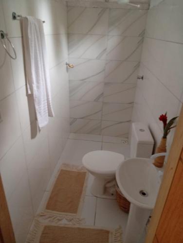 a white bathroom with a toilet and a sink at Pousada Eloy Beach in Trancoso