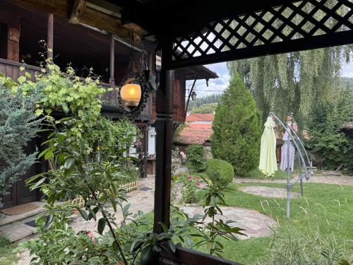 uitzicht op een tuin vanaf een veranda met een jurk op een standbeeld bij Мандулова Къща in Koprivshtitsa