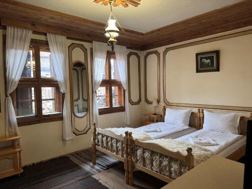 een slaapkamer met een bed in een kamer met ramen bij Мандулова Къща in Koprivshtitsa