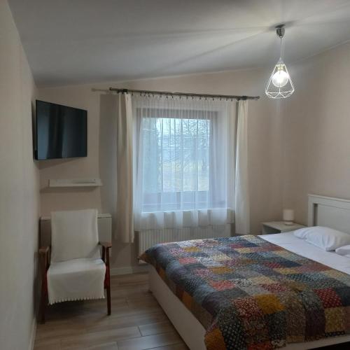 a bedroom with a bed and a chair and a window at Apartamenty Warka in Warka