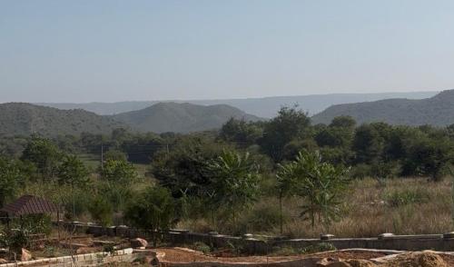 una vista de un campo con montañas en el fondo en THE RiYASAT SARISKA, en Ajabgarh