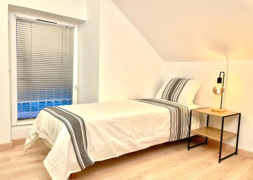 ein weißes Schlafzimmer mit einem Bett und einem Fenster in der Unterkunft Maison Villa Foch in Meaux