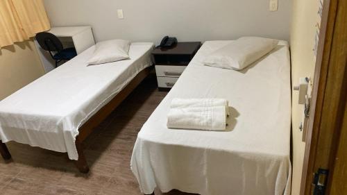 two beds with white sheets in a room at Campos Gerais Hotel - Próximo a Rodoviária e Mercados Turísticos in Belo Horizonte