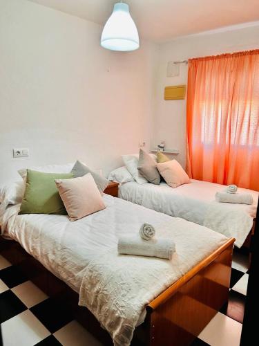 two beds in a room with a checkered floor at Casa Nieves, totalmente equipada Planta 2 in Arcos de la Frontera