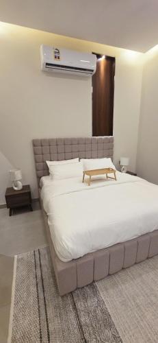 Un dormitorio con una gran cama blanca con cabecero marrón. en Nasma chalet, en Barka