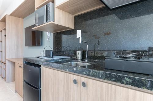 a kitchen with a sink and a stove at Max Carneiros Suítes - Conforto e sofisticação há alguns passos do mar! in Tamandaré