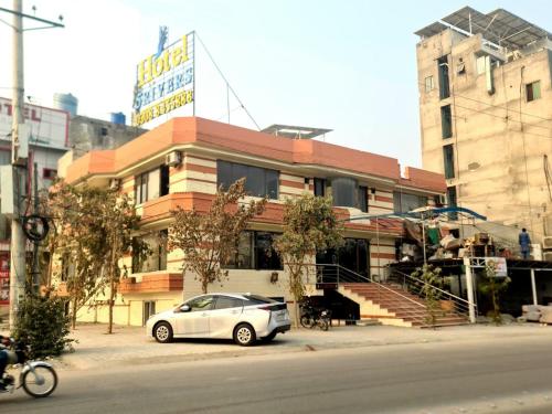 une voiture blanche garée devant un immeuble dans l'établissement Hotel Five Rivers - Airport Road, à Lahore