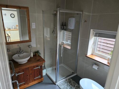 Birch Cottage with private wood fire hot tub في Harrietsham: حمام مزود بدش ومغسلة