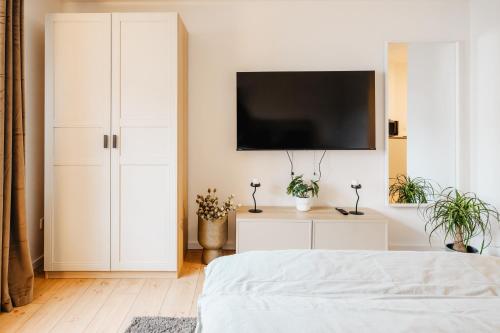 a white bedroom with a flat screen tv on a wall at Elegantes Apartment in Bad Pyrmont