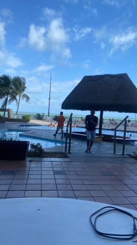 due persone sotto un ombrellone accanto a una piscina di Bugan Paiva flatpaivahome a Recife