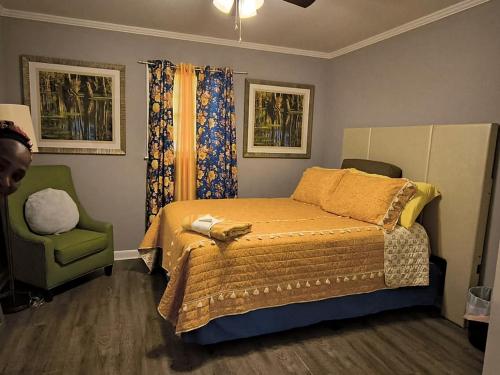 a bedroom with a bed and a green chair at Macon Duplex Getaway | 3BR, WiFi, BBQ & Parking in Riverside Park
