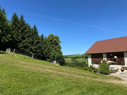 a barn on a hill next to a green field at Gîte le Frêne 