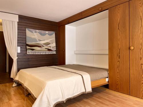 a small bedroom with a bed and a painting at Retro Alpine Studio - Terrace with Mountain View in Leukerbad