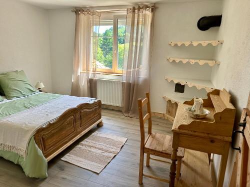 a bedroom with a bed and a desk and a window at Gîte le Frêne in Fuans