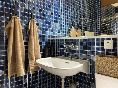 a blue tiled bathroom with a sink and towels at Retro Alpine Studio - Terrace with Mountain View in Leukerbad