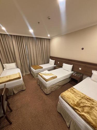 una habitación de hotel con 3 camas. en فندق التوحيد بارك 1 توصيل مجاني للحرم, en Al ‘Azīzīyah