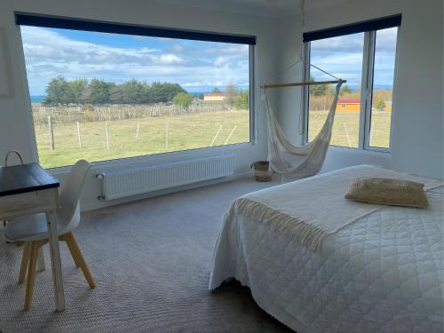 a bedroom with a bed and a desk and a large window at Casa Cálida entorno natural con vista al Estrecho in Leñadura