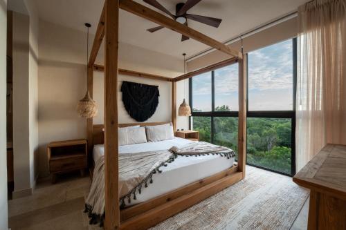 una camera con letto a baldacchino e ampia finestra di Oniric Condo Tulum a Tulum